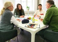 Gabriele Unützer, Katharina Temme, Phineas Speicher und Marcus Kolb sitzen gemeinsam am Tisch und diskutieren über eine Moderation.
